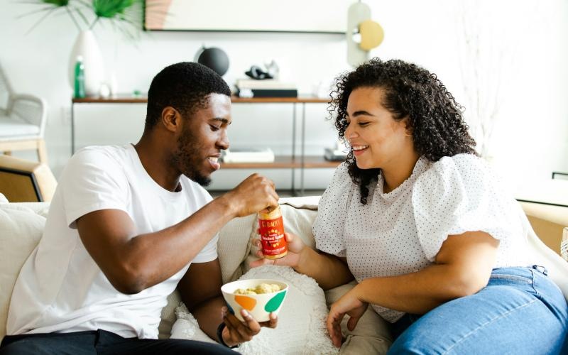 a man and a woman sitting on a couch and eating