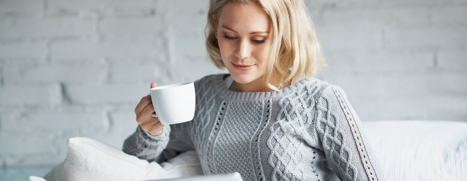 a woman drinking coffee on her sofa