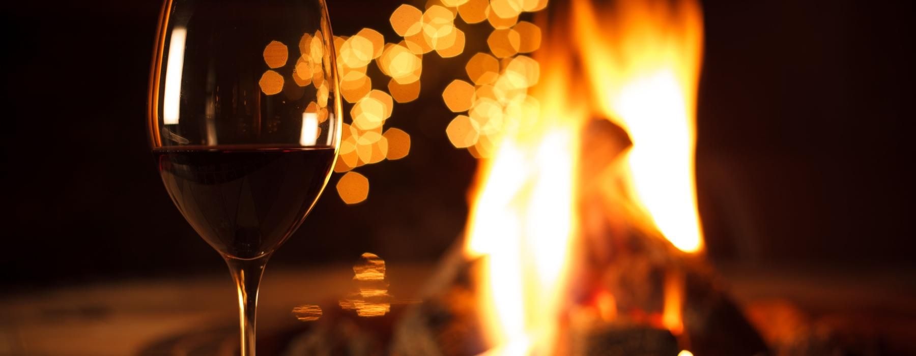 a glass of wine next to a fire