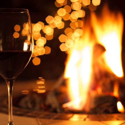 Everything within reach a glass of wine by a fire
